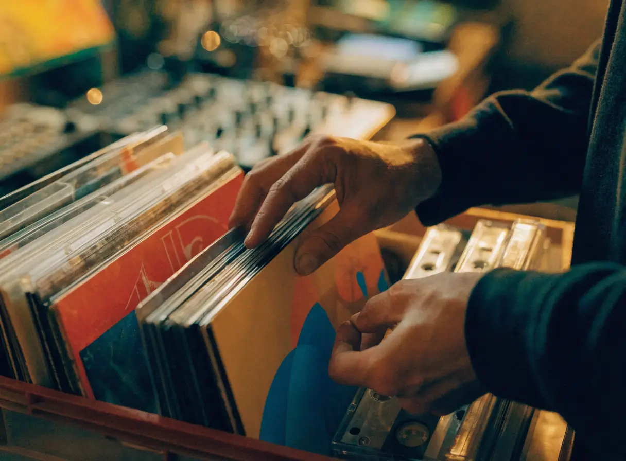 Hands flipping through a crate of vinyl records in a studio